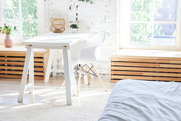Stylish loft modern home office interior. Spacious design apartment with light walls large windows and writing desk. Clean modern decoration with elegant furniture in minimalist Scandinavian style.