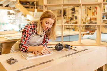 hardworking caucasian woman woodworker make drawings, young lady loves her job in factory