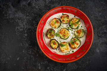 Tasty fried zucchini slices on a plate with sauce on a wooden table. Picnic snack. Rustic style. Top view, flat lay.