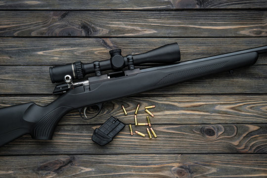 Bolt small caliber rifle 22lr with an optical sight on a wooden back. Hunting small-caliber weapon on a wooden table.