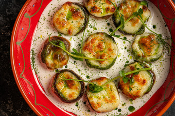 Tasty fried zucchini slices on a plate with sauce on a wooden table. Picnic snack. Rustic style. Top view, flat lay.