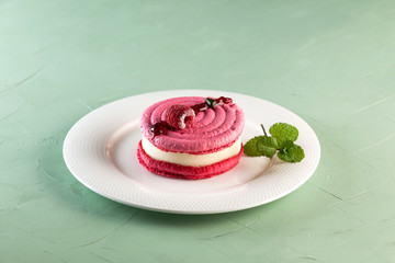 Vanilla-berry dessert based on macaroons cakes. Structural background of pistachio color. Closeup. Copy space