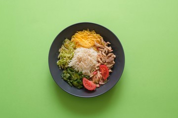 Traditional Korean dish Kuksi on green background ( one of the types of Kuksi). Ingredients- pasta, vegetable salads of cucumbers, cabbage, radish, meat, omelet. The broth is served separately.