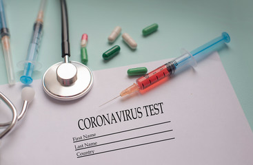 a syringe with a blood test and a stethophonendoscope with a patient questionnaire and tablets for a pandemic of a cornovirus