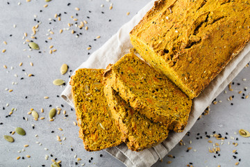 Healthy content. Loaf of pumpkin bread, seeds, sliced pieces, top view, close up. Grey background