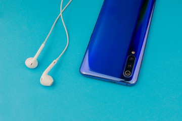 modern smartphone with musical headphones on a blue background