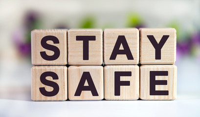 STAY SAFE - text on wooden cubes on a floral background with tulip buds