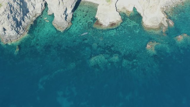 The sea of ​​Pantelleria with its jagged and volcanic coast. Turquoise colored sea. Dammusi, typical houses of Pantelleria.