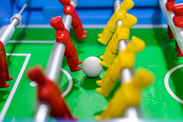 Futebol de mesa, pebolim de mesa, bonecos de times vermelhos e amarelos com bola branca ao centro.