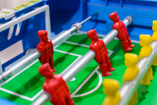 Futebol de mesa, pebolim de mesa, times de bonecos vermelhos e amarelos posicionados na mesa de futebol.