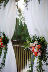 beautiful floral arrangements hung on white cloth draped on wedding ceremony arch