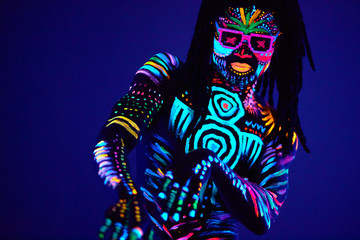portrait of black african man in fluorescent patterns dancing in ultraviolet light, young dancer with fluorescent glowing makeup move