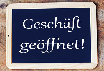 Auf einer Schreibtafel steht in deutsch: Gesch&auml;ft ge&ouml;ffnet!