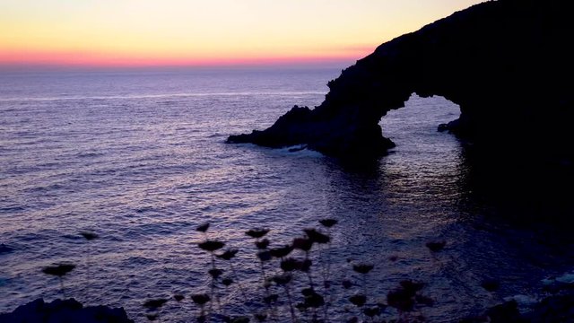 Arco dell'Elefante in Pantelleria Sicily during sunrise. Rock formation of a faraglione whose shape resembles an elephant with its trunk immersed in the water to form the arch.