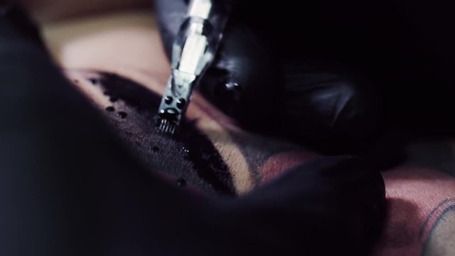 emotional closeup macro on needle tattoo machine in slow motion. Woman skin with black ink tattoo