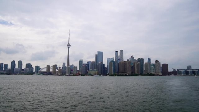 Sailboat floats by as Toronto Island Ferry drifts away from downtown waterfront skyline