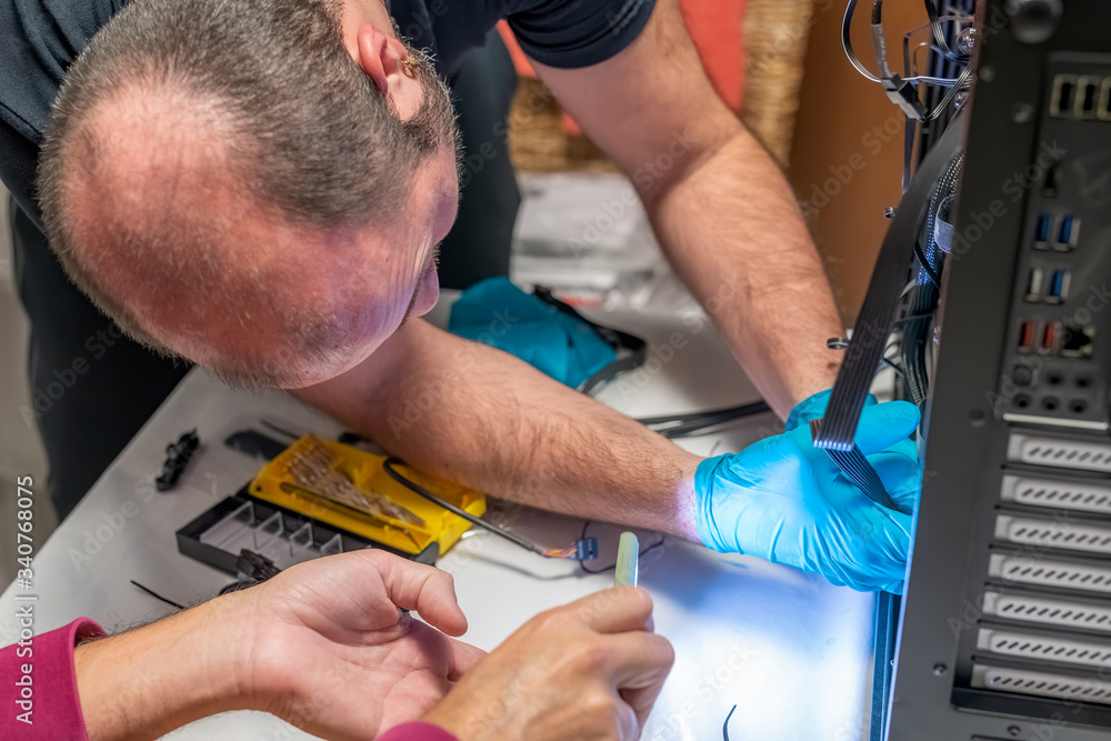 Poster personal computer technicians assembling new pc with the help of smartphone light