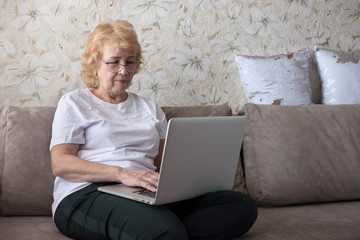 Retired woman studying on laptop at home. Online education for seniors