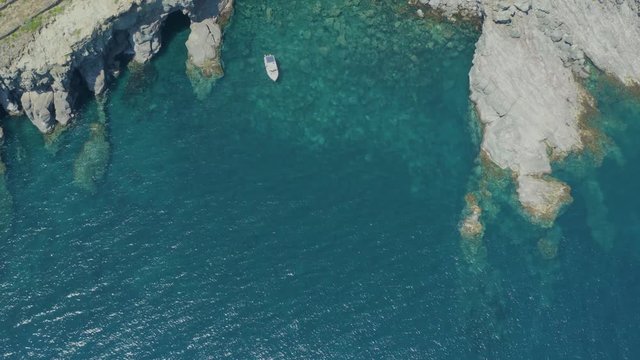 The sea of ​​Pantelleria with its jagged and volcanic coast. Turquoise colored sea. Dammusi, typical houses of Pantelleria.
