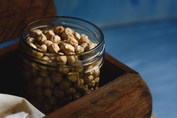 Raw chickpeas in a glass jar and wood spoon.