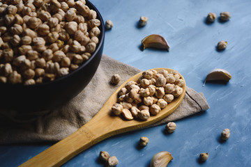 Raw chickpeas in a bowl and wood spoon.