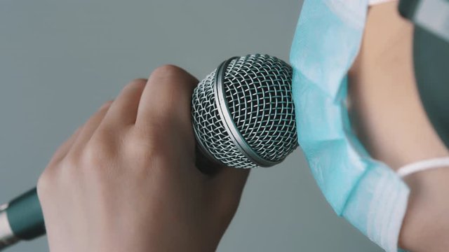 Young singer singing in the microphone fith face mask in home studio. Remote work, self issolation and prevention of coronavirus spread