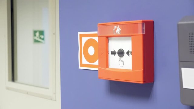 Fire alarm button and exit direction sign on stairs in office