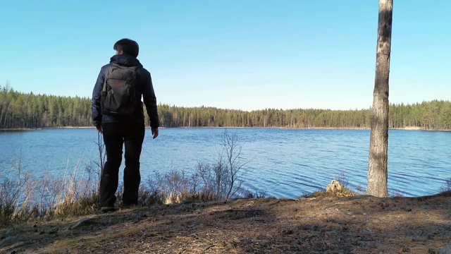Fagersta, Sweden - April 18, 2020: A middle-aged woman came to the lake, took out a mobile phone from her pocket, took a picture of the lake and left.
