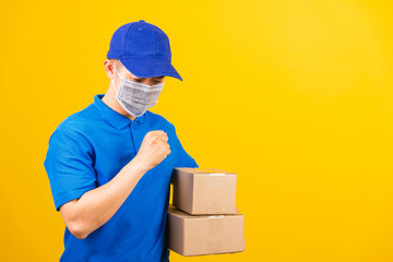 Obraz na płótnie Canvas Asian young delivery worker man in blue t-shirt and cap uniform wearing face mask protective he sneezing during service customer under coronavirus or COVID-19, studio shot isolated yellow background