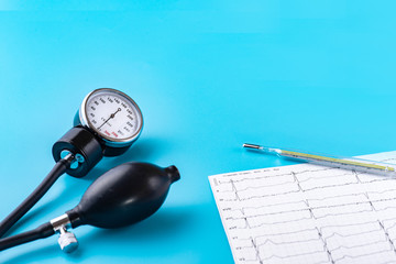 Device for measuring blood pressure, tonometer, ECG, thermometer on blue background. Copy-space.
