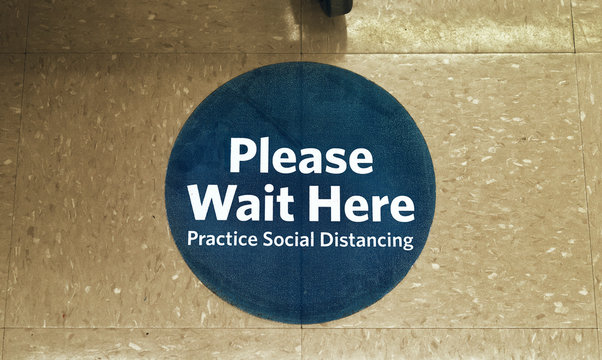 Round Blue Sign On Supermarket Floor Asking Customers To Practice Social Distancing