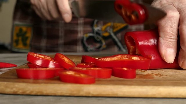 Using Knife To Cutting Ramiro Red Hot Pepper On Cutting Wooden Board. Top View. Panning Slider Shot. Close Up..