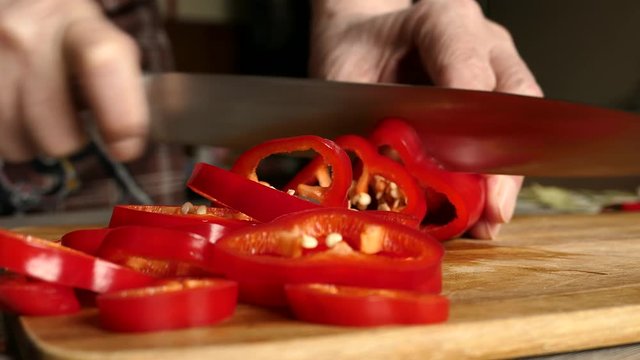 Using Knife To Cutting Ramiro Red Hot Pepper On Cutting Wooden Board. Top View. Zoom In Slider Shot. Close Up..