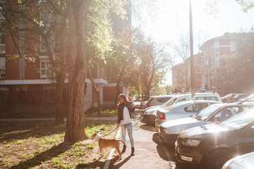 A beautiful caucasian girl with a dog walks down the street