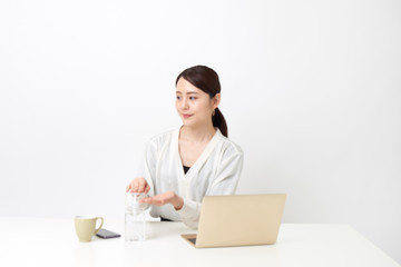 リモートワークしながら手の消毒をしている女性