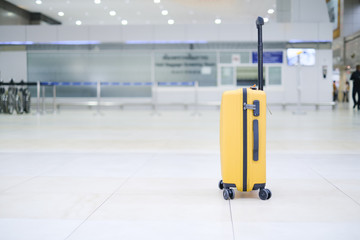 Close up mock up brand tag or name tag tied to yellow thick suitcase, concept of product logo design template on travelling tourism, travel through destination in airport, with blur bright background
