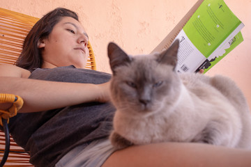 Mujer lee con gato en terraza