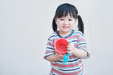 cute asian little girl playing with toys in sandbox having fun feeling happy and enjoying play time, staying at home out door making mess and using imagination for learning doing practical activities