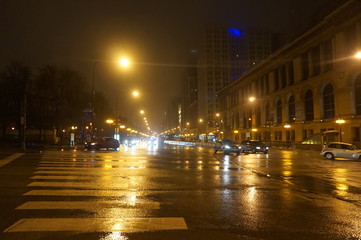 Fototapeta na wymiar Chicago, Illinois / USA - December,25, 2016. Chicago downtown streets intersection. Rainy weather causes light reflection on the asphalt. Yellow street lights represent urban architecture. Many cars.