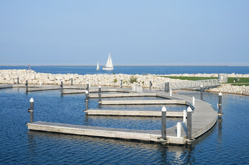 Milwaukee, Illinois/ USA - 09.03.15. Lake Michigan coast line. Boat Marina with  white rocks and docks. Blue color of water and white sailing boats on the water. Great view of water line.