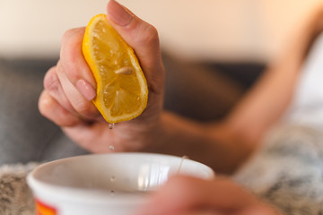 A sick caucasian girl squeezes lemon and pours it into tea
