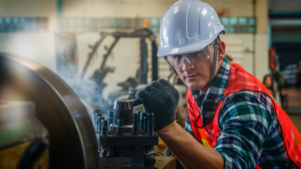 industrial background of caucasian mechanics engineer operating lathe machine for metalwork in...
