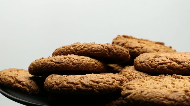 Rotating Close Up Of Fresh Brown Oatmeal Cookies On A Black Plate On A White Background.