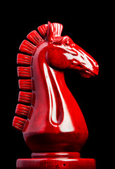 Wooden chess knight in red with black background
