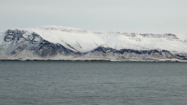 Long shot right to left pan of Reykjavik snowy Esja mountain