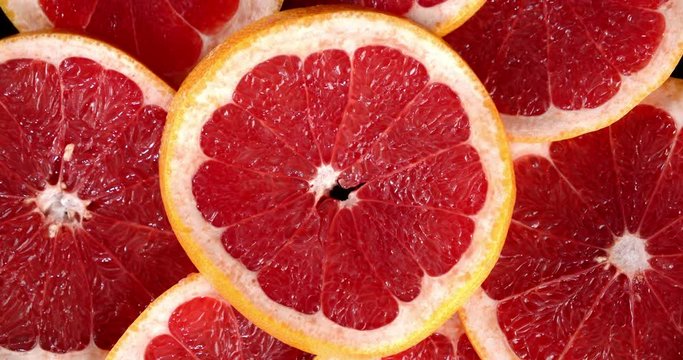Red round slices of grapefruit slowly rotate.