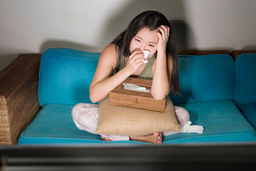 young cute and emotional Asian Chinese woman watching korean drama show on TV sitting at home...