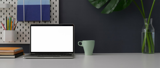 Close up view of home office desk with blank screen laptop, supplies, decorations and copy space