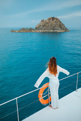 Tourists women with long beautiful hair wearing white dresses, standing looking at the sea view. She stands on white aboard boat With a happy posture