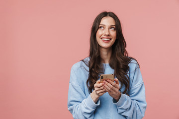 Image of joyful young woman looking upward and using cellphone